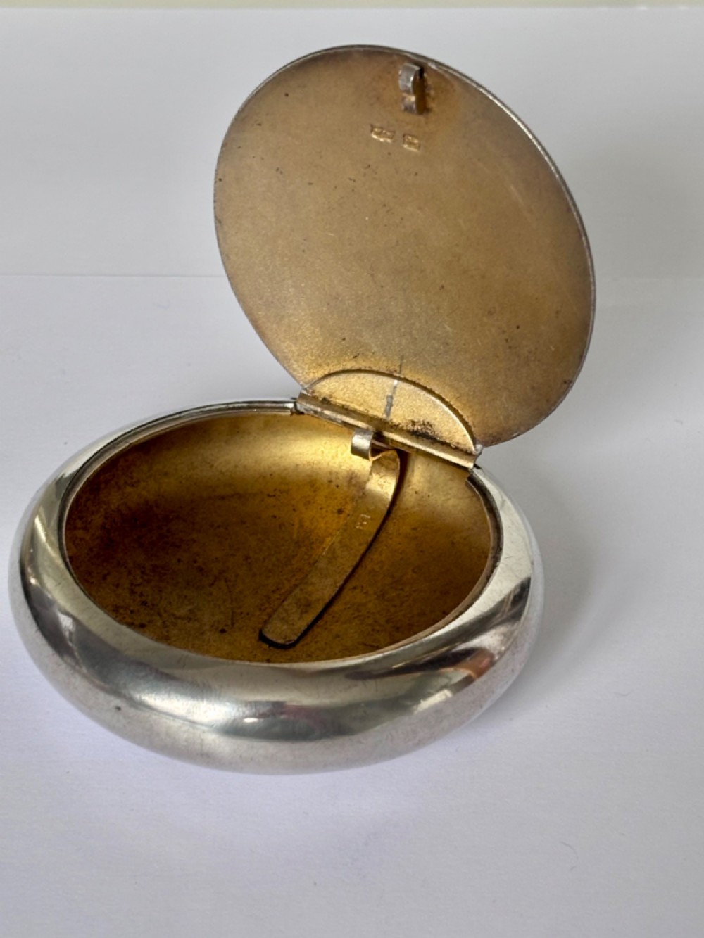 An Edwardian oval sterling silver squeeze tobacco box with a polished finish and rounded pebble profile. View II
