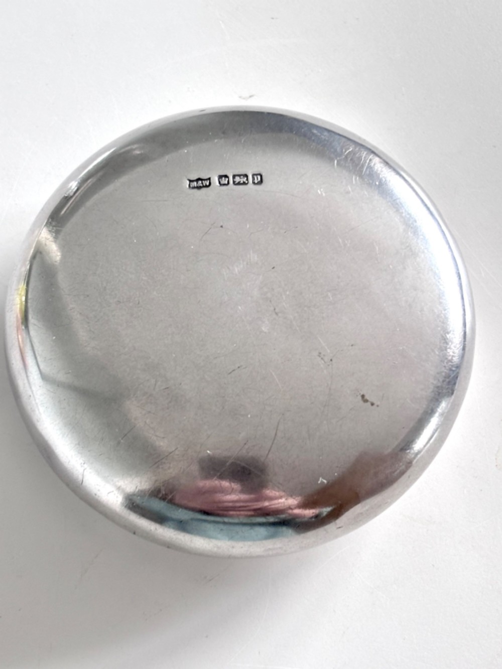 An Edwardian oval sterling silver squeeze tobacco box with a polished finish and rounded pebble profile. View IV