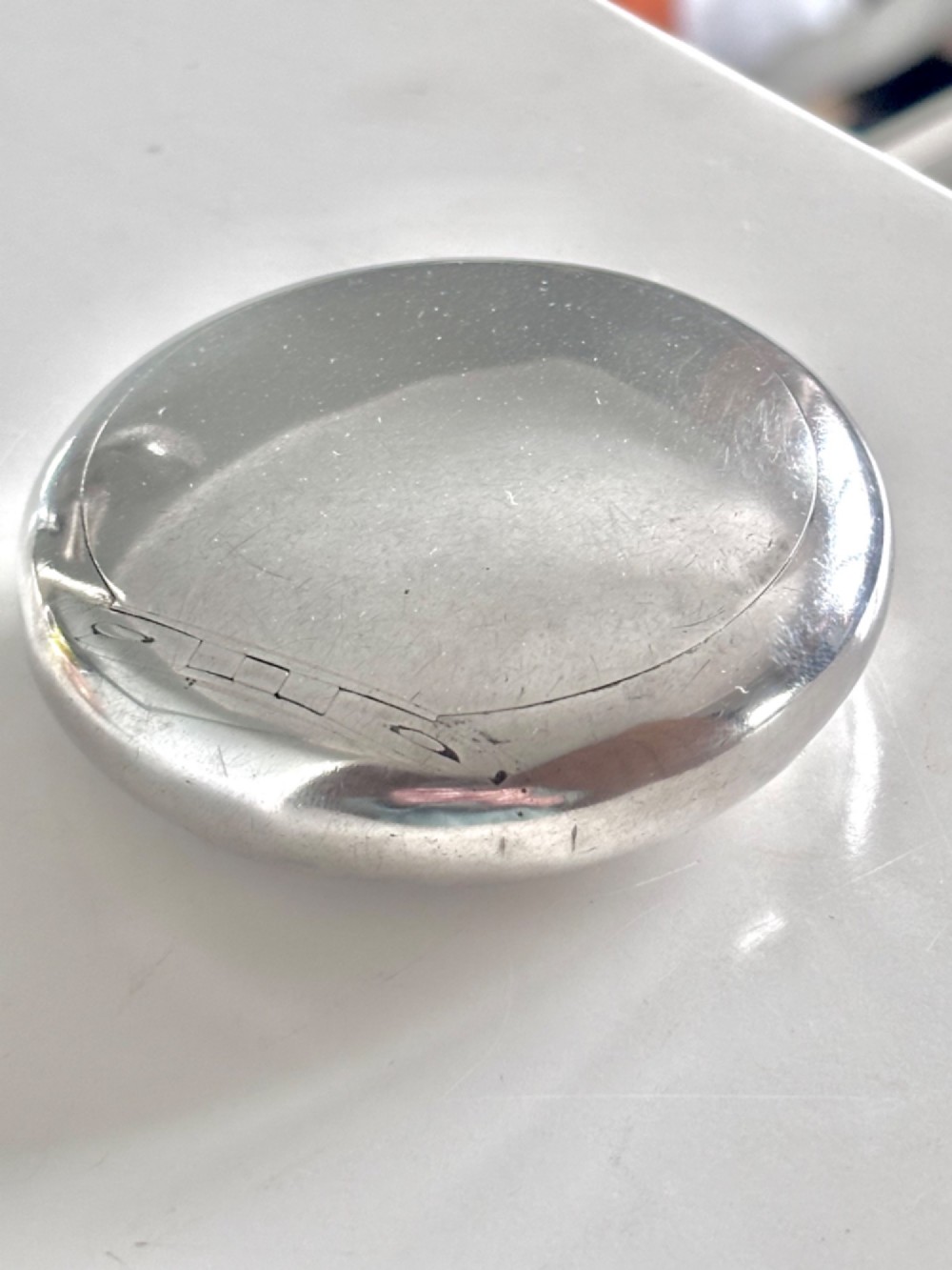 An Edwardian oval sterling silver squeeze tobacco box with a polished finish and rounded pebble profile. View VI