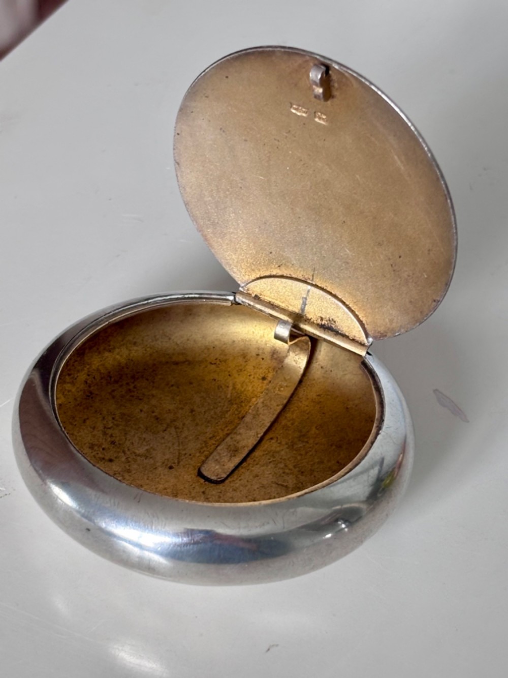 An Edwardian oval sterling silver squeeze tobacco box with a polished finish and rounded pebble profile. View VII