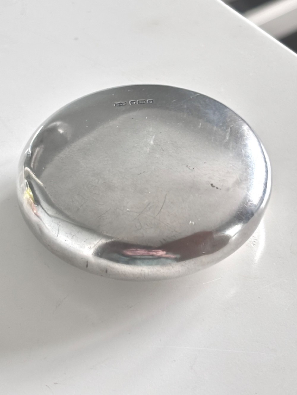 An Edwardian oval sterling silver squeeze tobacco box with a polished finish and rounded pebble profile. View VIII