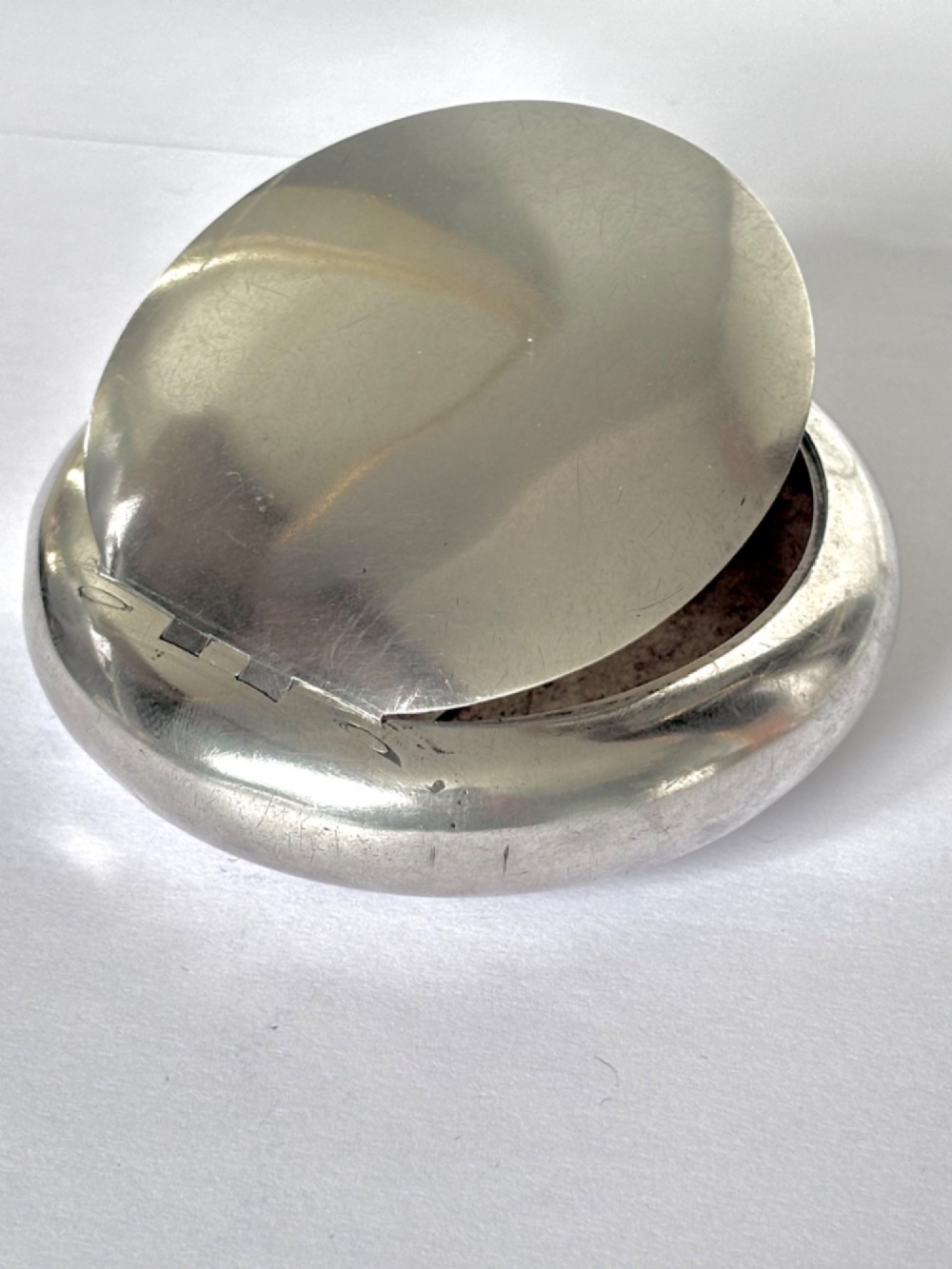 An Edwardian oval sterling silver squeeze tobacco box with a polished finish and rounded pebble profile. View XI