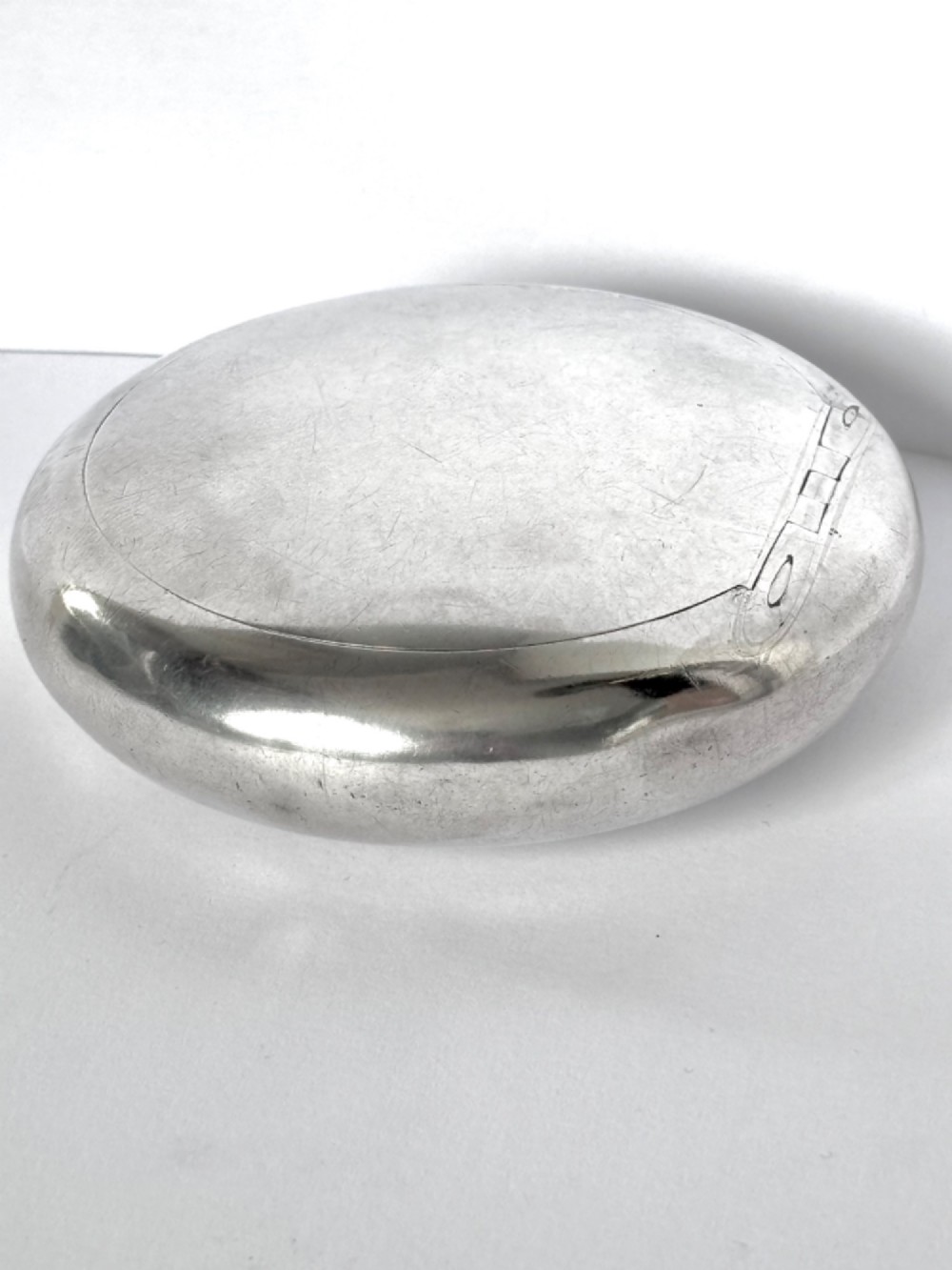 An Edwardian oval sterling silver squeeze tobacco box with a polished finish and rounded pebble profile. View XIII