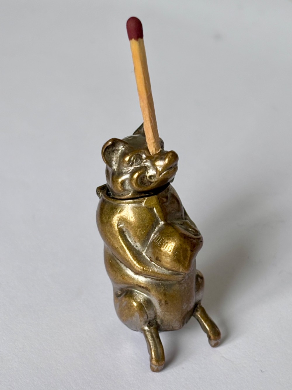 A small antique cast brass vesta case formed in the shape of a pig sitting upright.