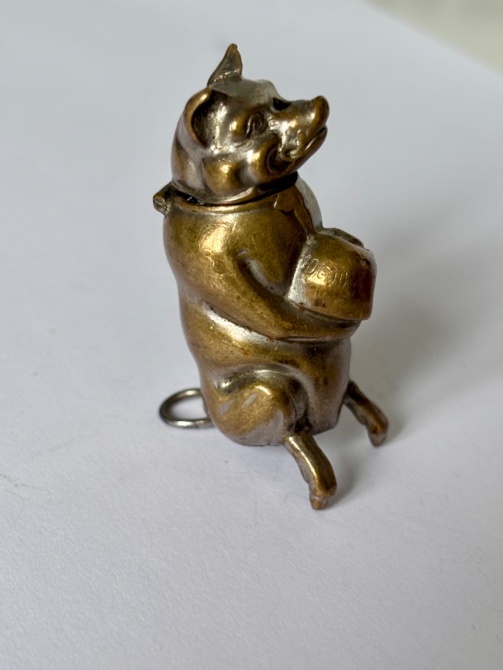 A small antique cast brass vesta case formed in the shape of a pig sitting upright. View VIII