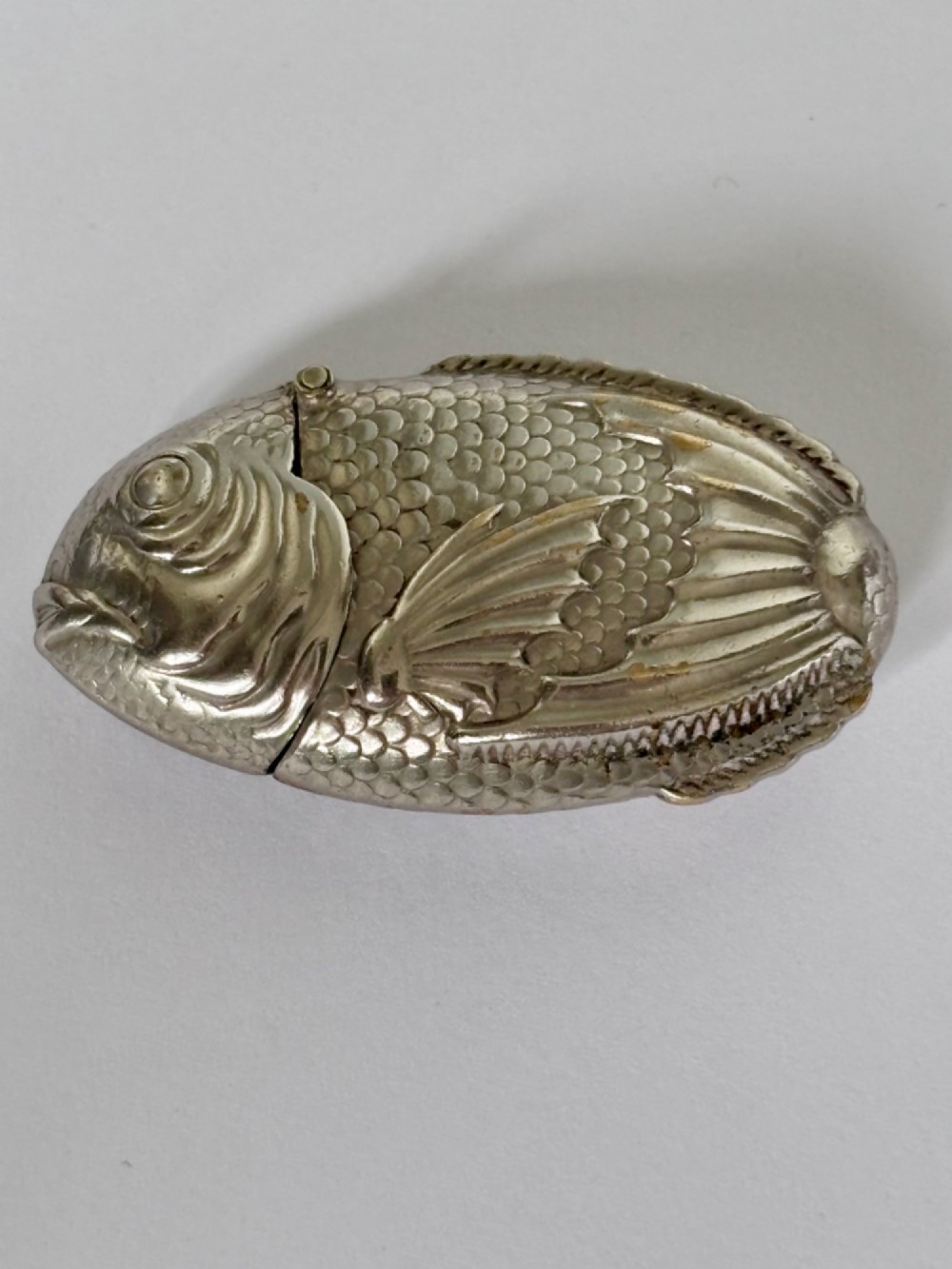 A silver-plated brass vesta case cast in the shape of a carp with detailed body scales and a hinged head.