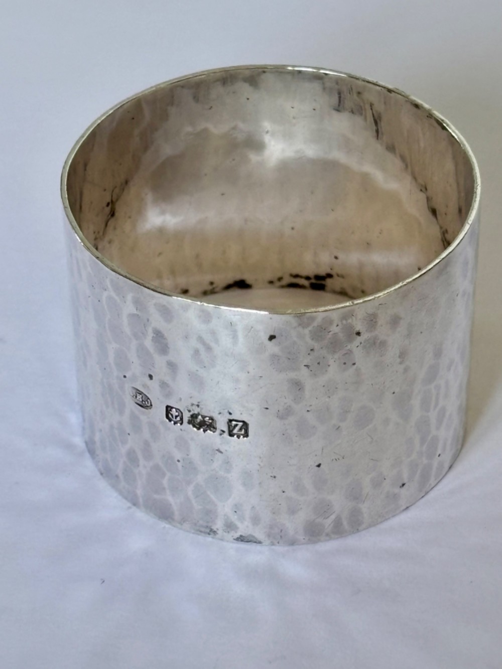 A wide, cylindrical sterling silver napkin ring featuring a hand-hammered planished surface finish. View II
