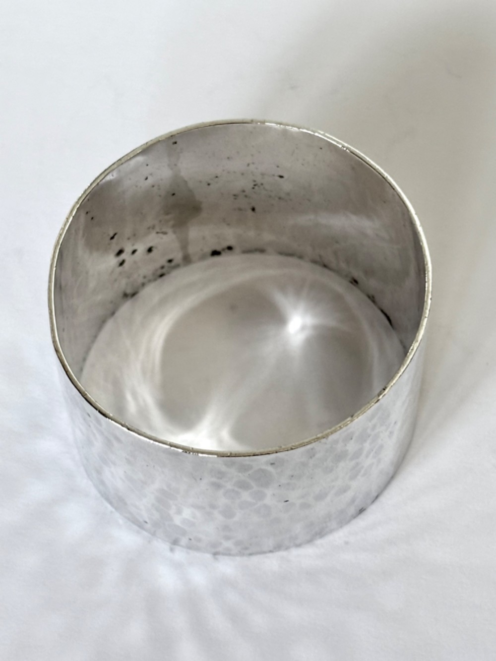 A wide, cylindrical sterling silver napkin ring featuring a hand-hammered planished surface finish. View V