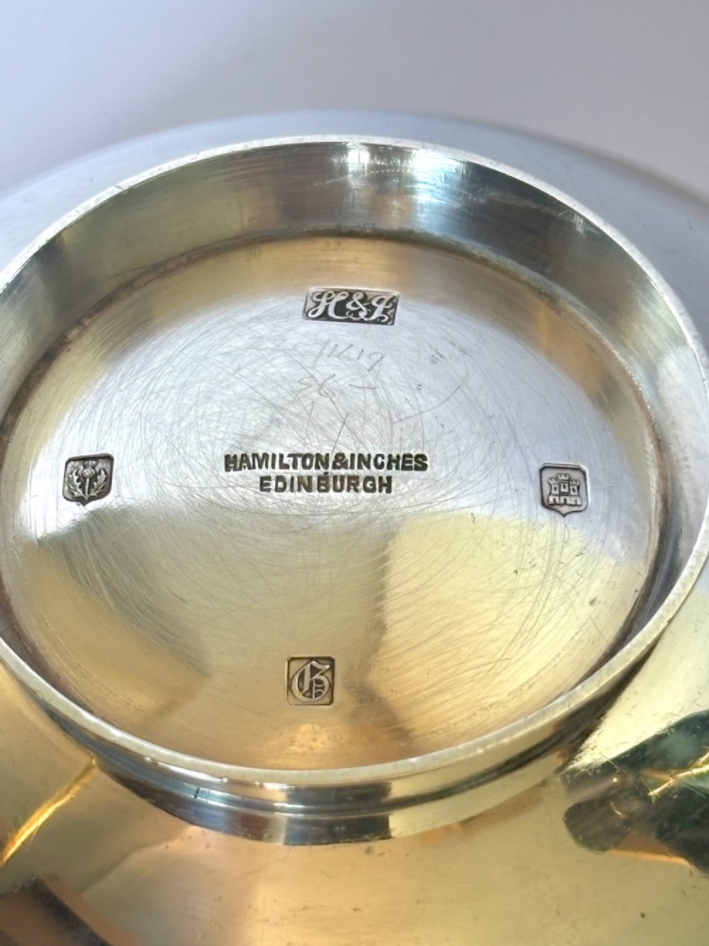A shallow sterling silver quaich featuring two flattened lug handles, a circular pedestal base, and a band of embossed Celtic knotwork along the upper rim. View III