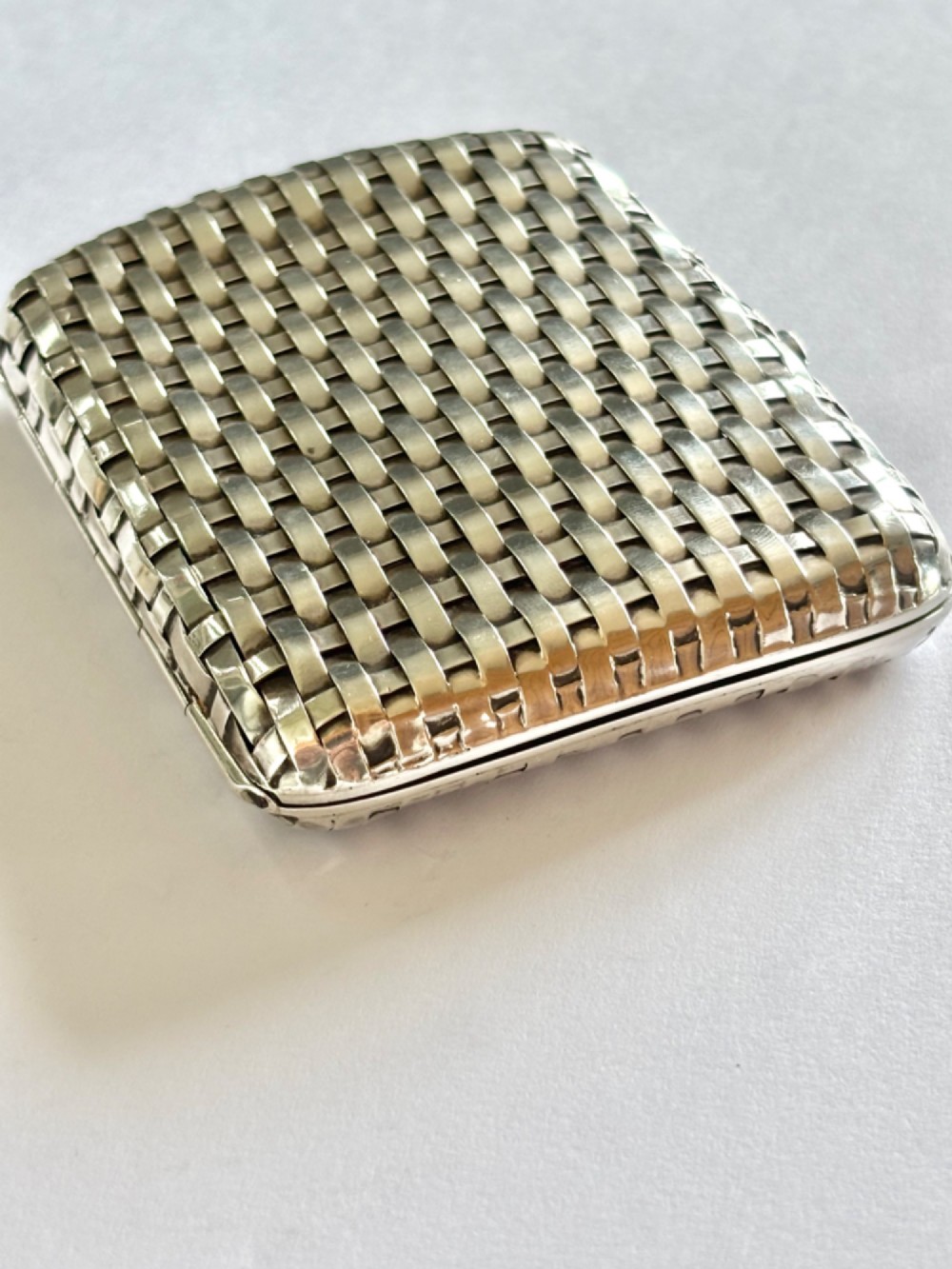An early 20th-century rectangular silver cigarette case with a textured basketweave pattern and a side release button. View III