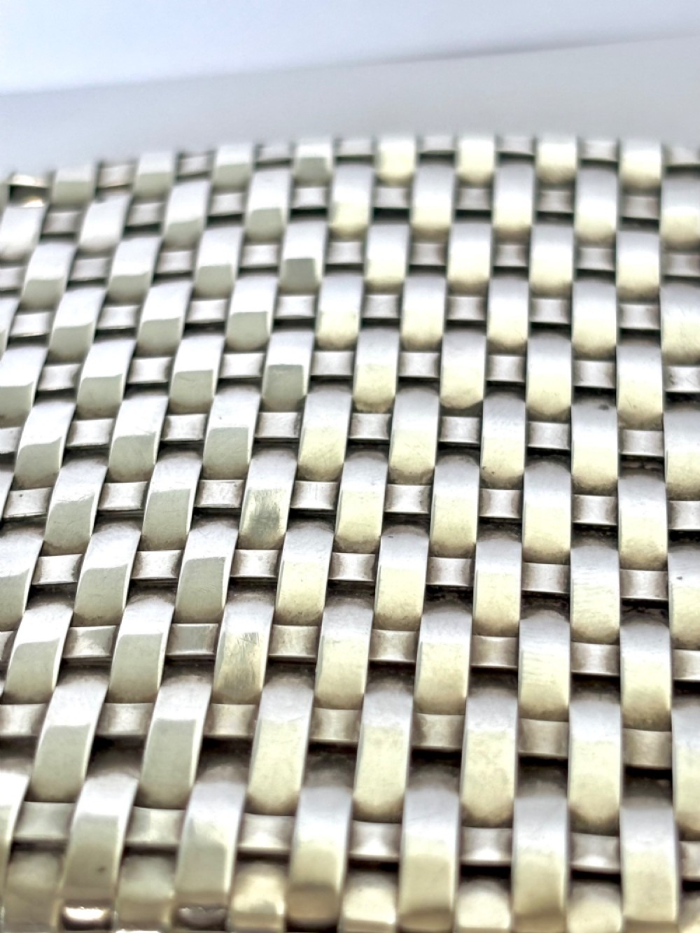 An early 20th-century rectangular silver cigarette case with a textured basketweave pattern and a side release button. View IV