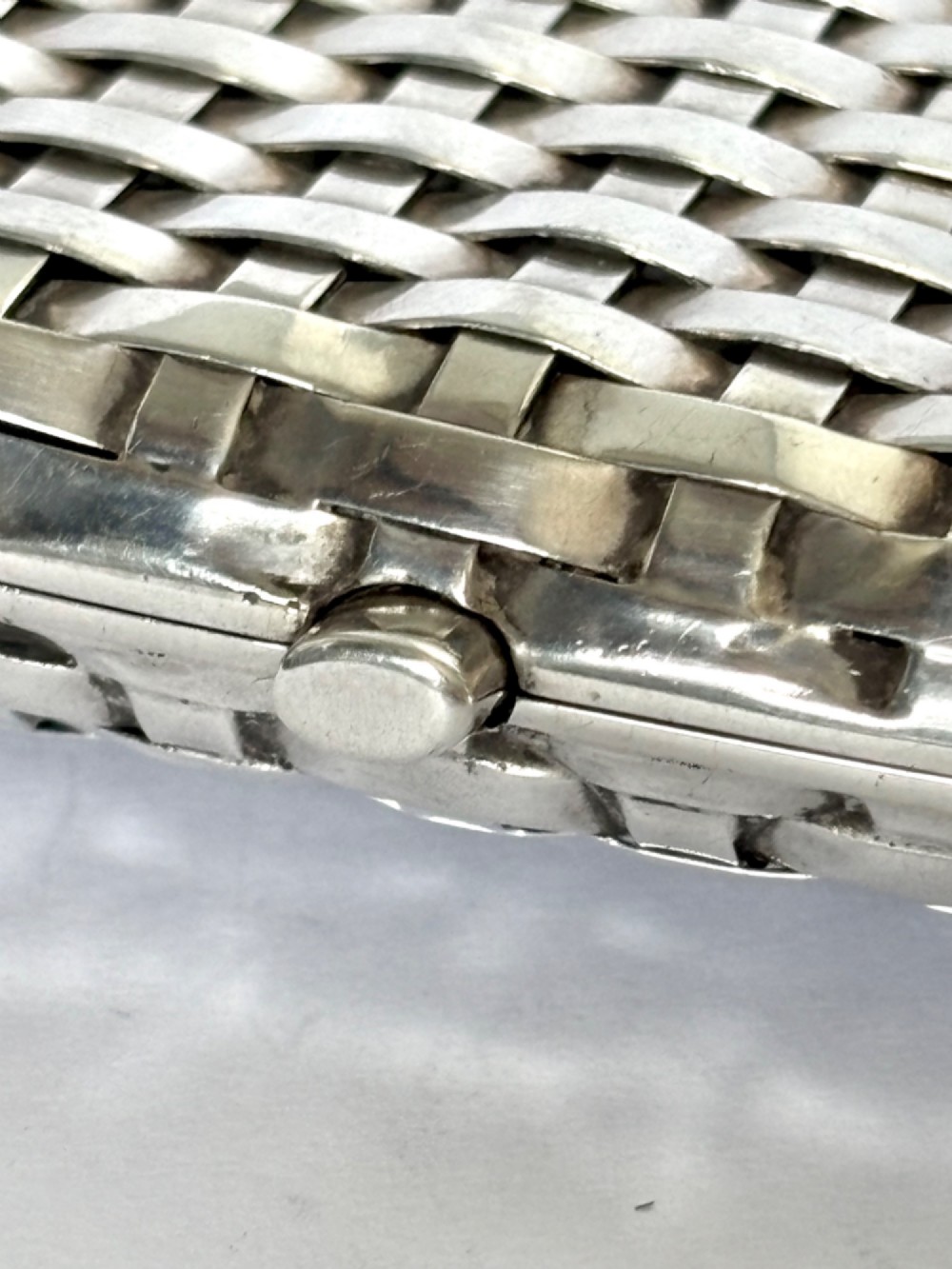 An early 20th-century rectangular silver cigarette case with a textured basketweave pattern and a side release button. View IX