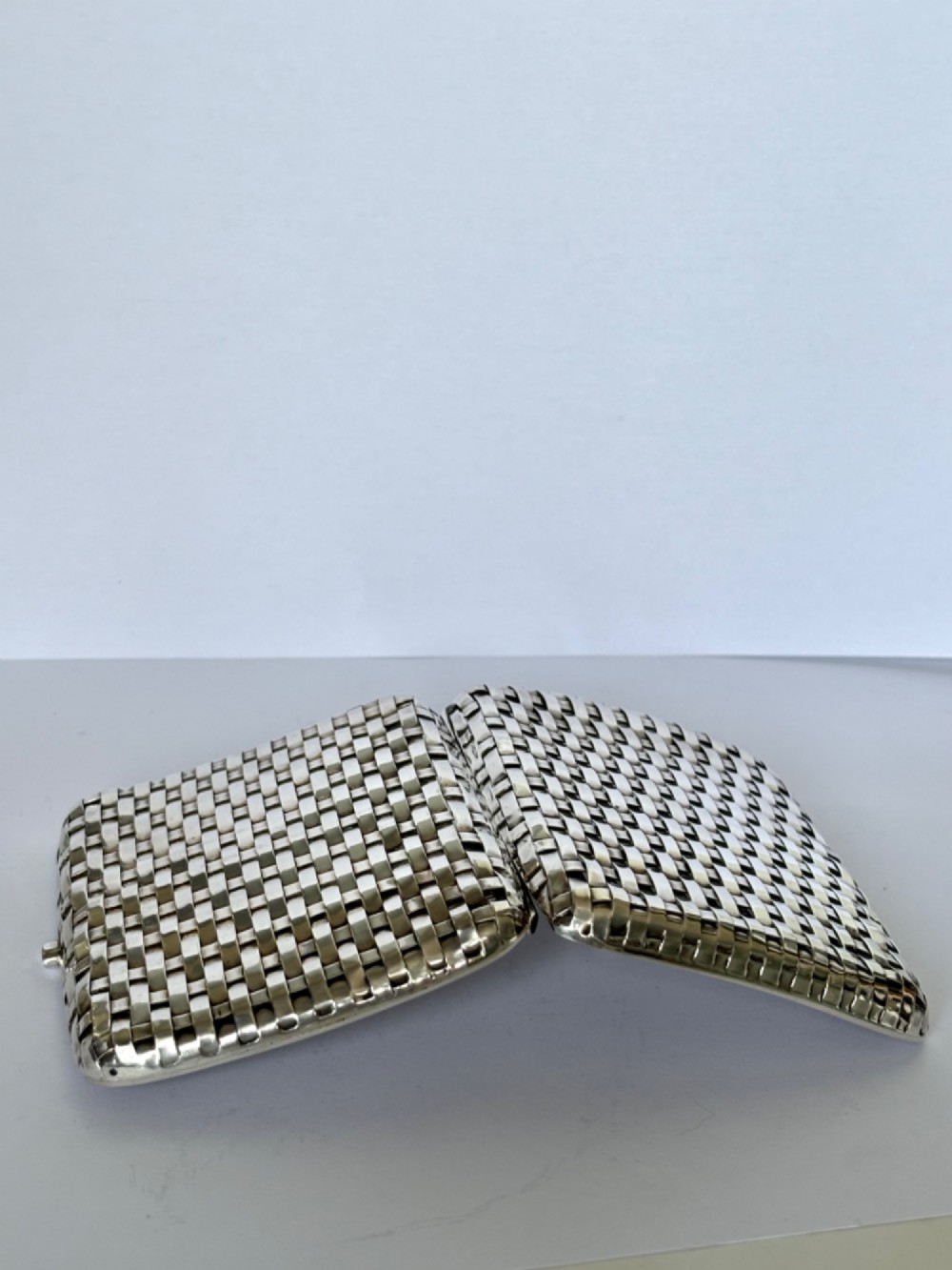An early 20th-century rectangular silver cigarette case with a textured basketweave pattern and a side release button. View XI