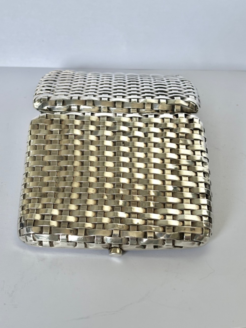 An early 20th-century rectangular silver cigarette case with a textured basketweave pattern and a side release button. View XII