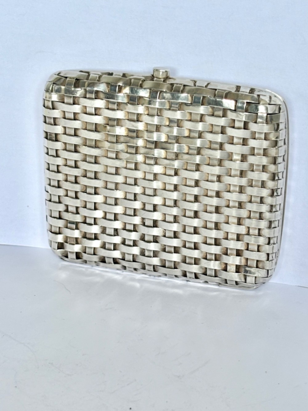 An early 20th-century rectangular silver cigarette case with a textured basketweave pattern and a side release button. View XIII