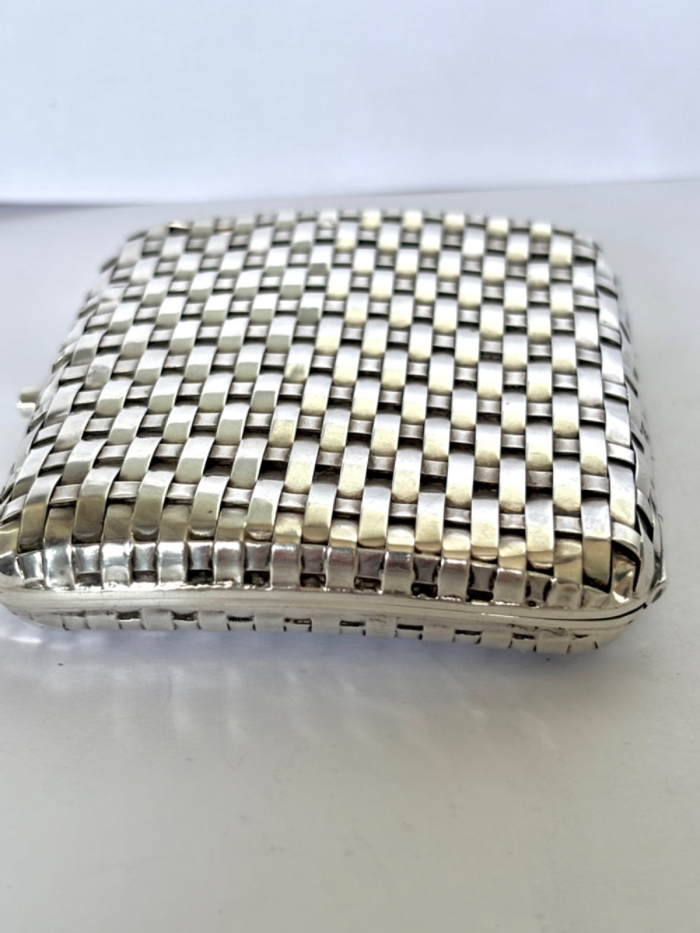 An early 20th-century rectangular silver cigarette case with a textured basketweave pattern and a side release button. View XIV