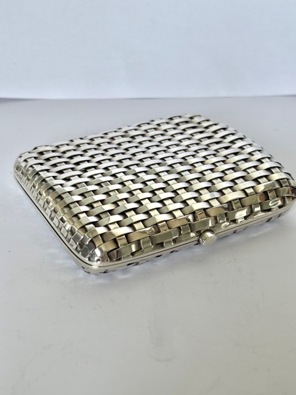 An early 20th-century rectangular silver cigarette case with a textured basketweave pattern and a side release button. View XV