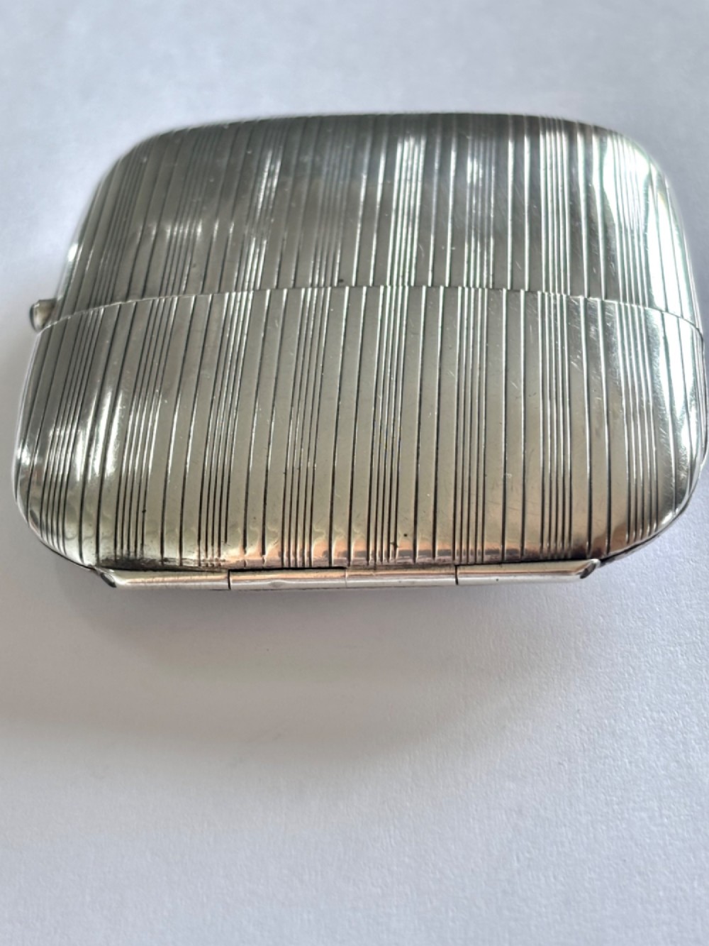 An Art Deco Continental 900 silver gilt cigarette case featuring horizontal engine-turned reeding and a blue cabochon push button. View II