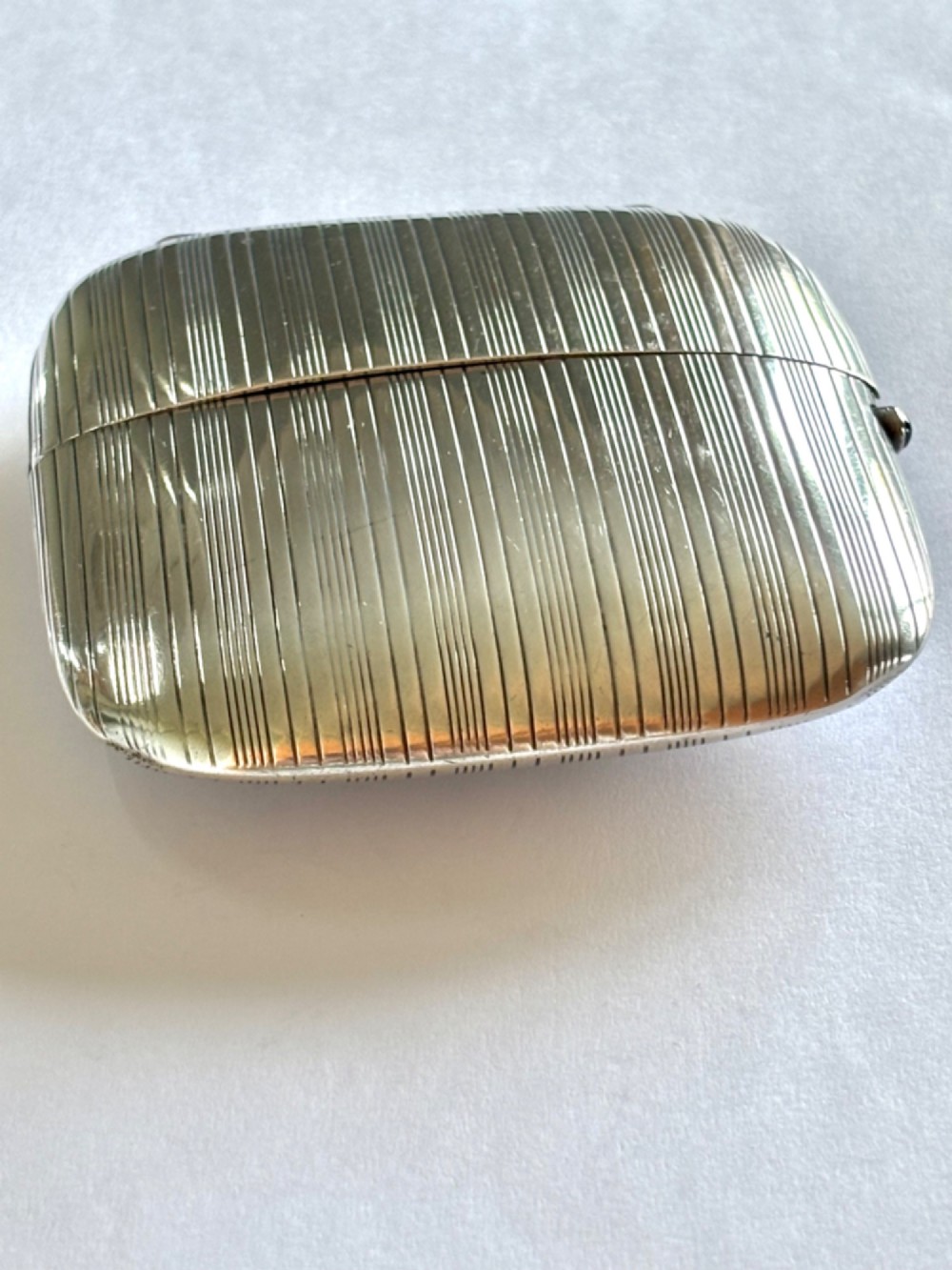 An Art Deco Continental 900 silver gilt cigarette case featuring horizontal engine-turned reeding and a blue cabochon push button. View VI