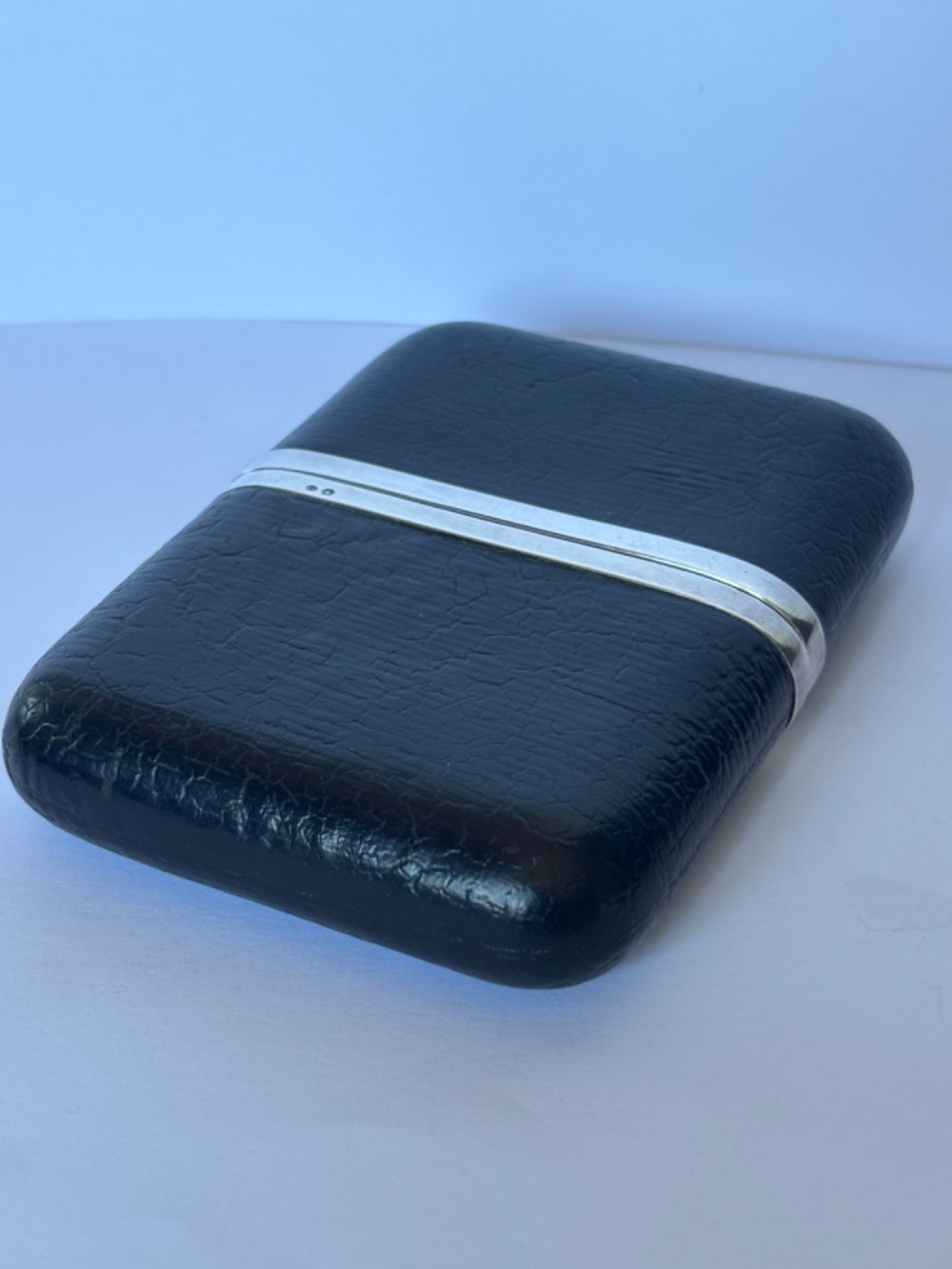 An antique black textured leather cigar case featuring a central hallmarked 900 silver collar.