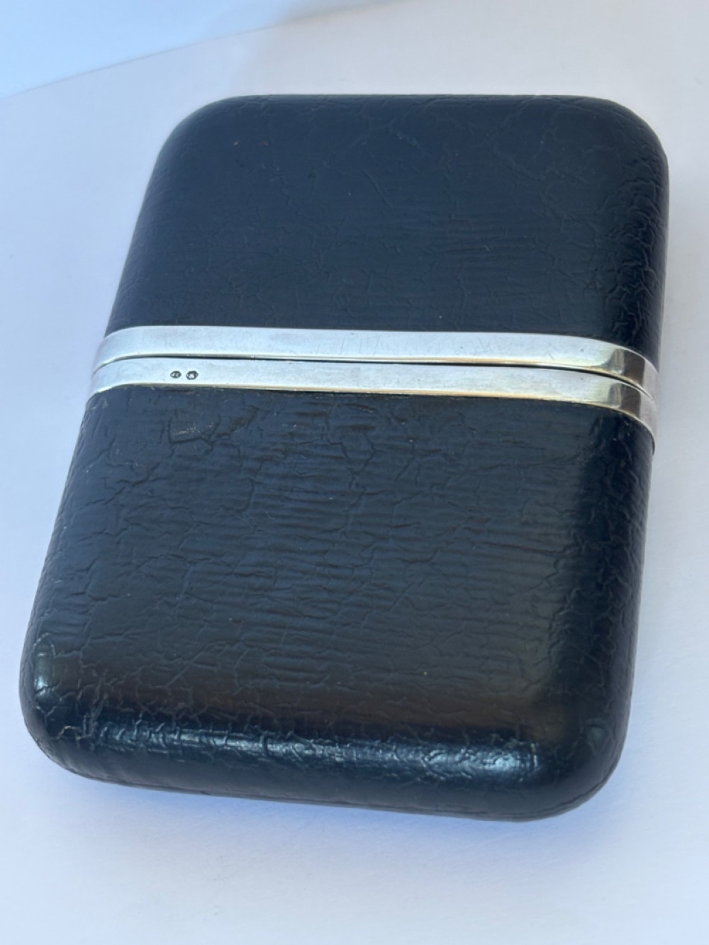 An antique black textured leather cigar case featuring a central hallmarked 900 silver collar. View II