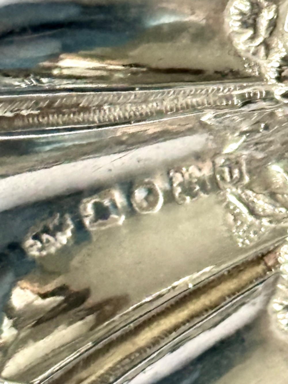 A Victorian sterling silver tea caddy spoon featuring a fluted shell-shaped bowl with embossed floral detailing and a hallmarked handle. View VIII