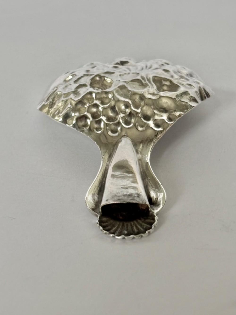 A Victorian sterling silver tea caddy spoon featuring a fluted shell-shaped bowl with embossed floral detailing and a hallmarked handle. View IX