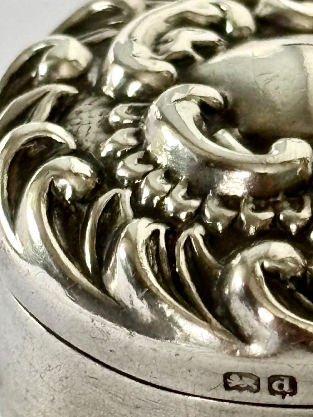 A small circular Edwardian sterling silver gilt trinket box with embossed scrollwork decoration on the lid. View VII