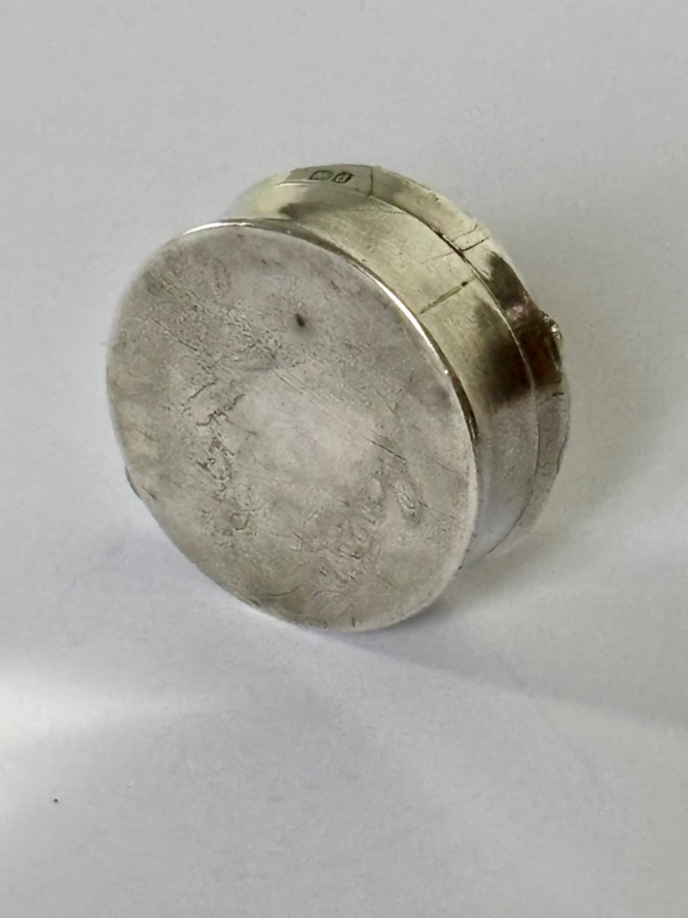 A small circular Edwardian sterling silver gilt trinket box with embossed scrollwork decoration on the lid. View VIII