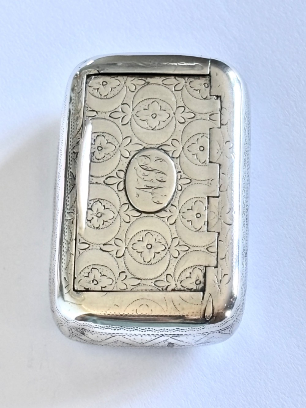 A small rectangular George III sterling silver snuff box with bright-cut floral engraving and a central oval cartouche. View II
