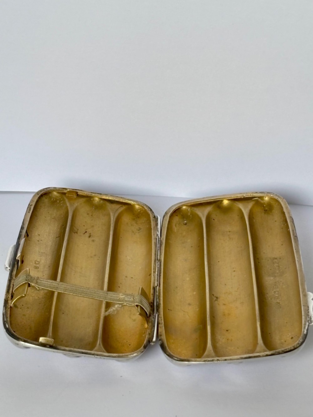 An Edwardian sterling silver triple cigar case featuring engraved foliate scrollwork and three rounded channels. View V