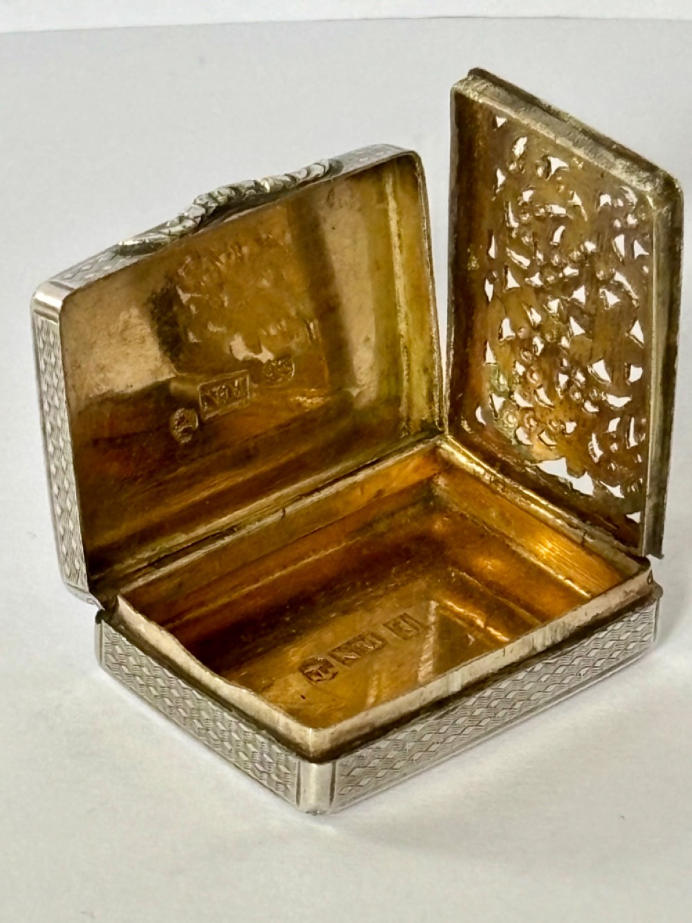 A small open rectangular silver-gilt box featuring a finely pierced floral inner grille and engraved lid detailing. View IV