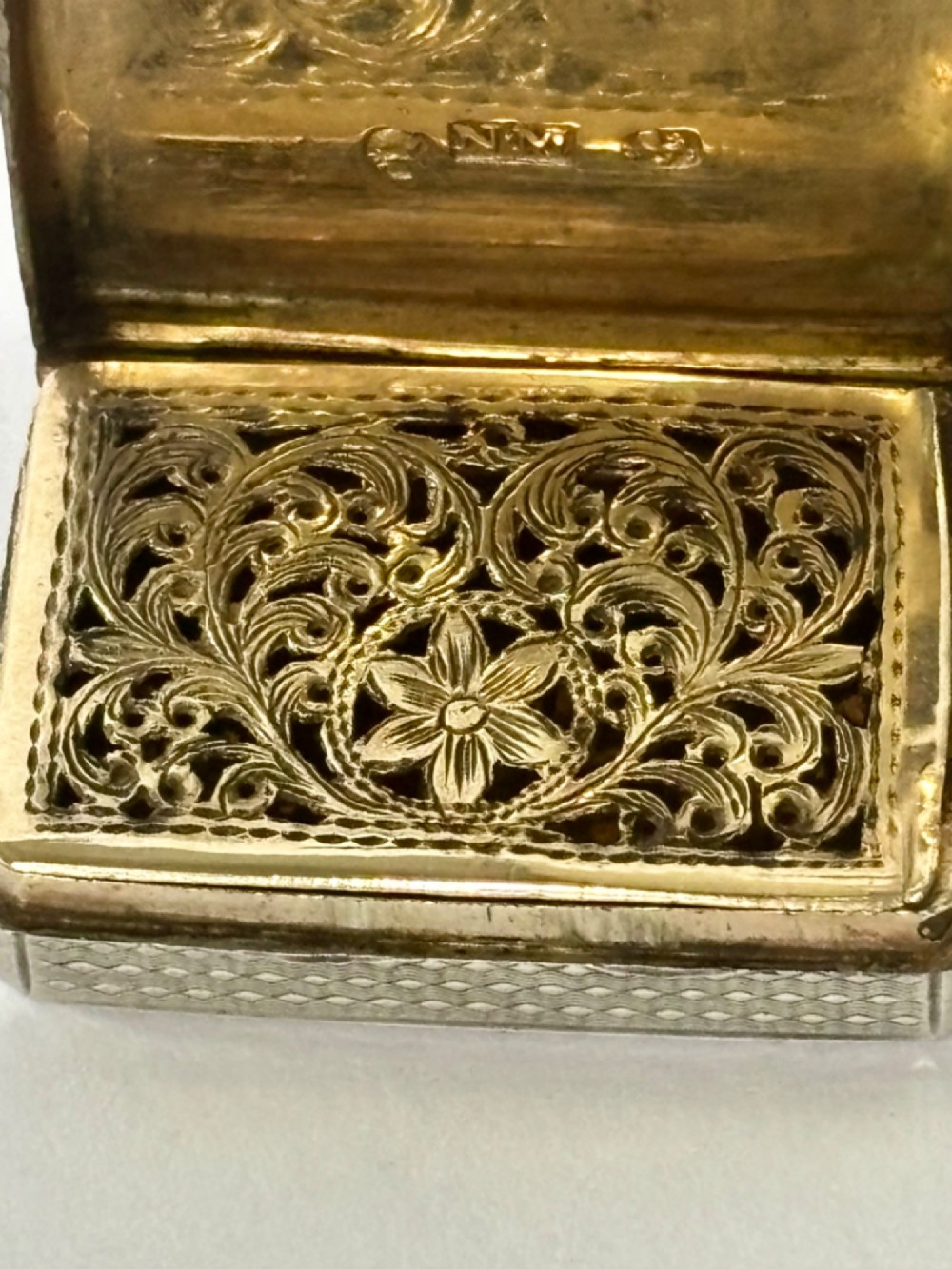 A small open rectangular silver-gilt box featuring a finely pierced floral inner grille and engraved lid detailing. View X