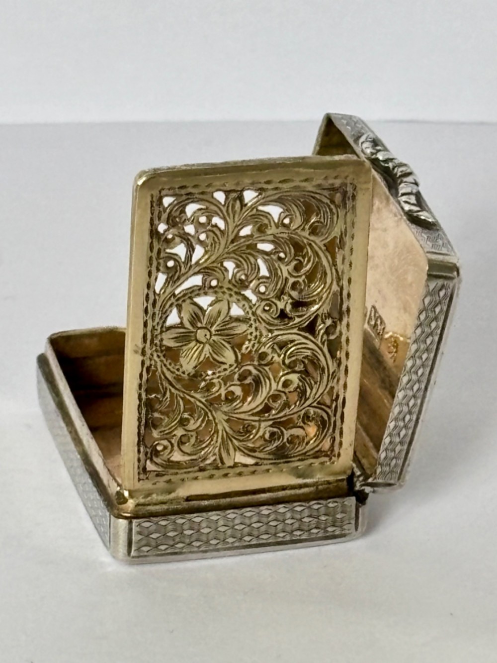 A small open rectangular silver-gilt box featuring a finely pierced floral inner grille and engraved lid detailing. View XII
