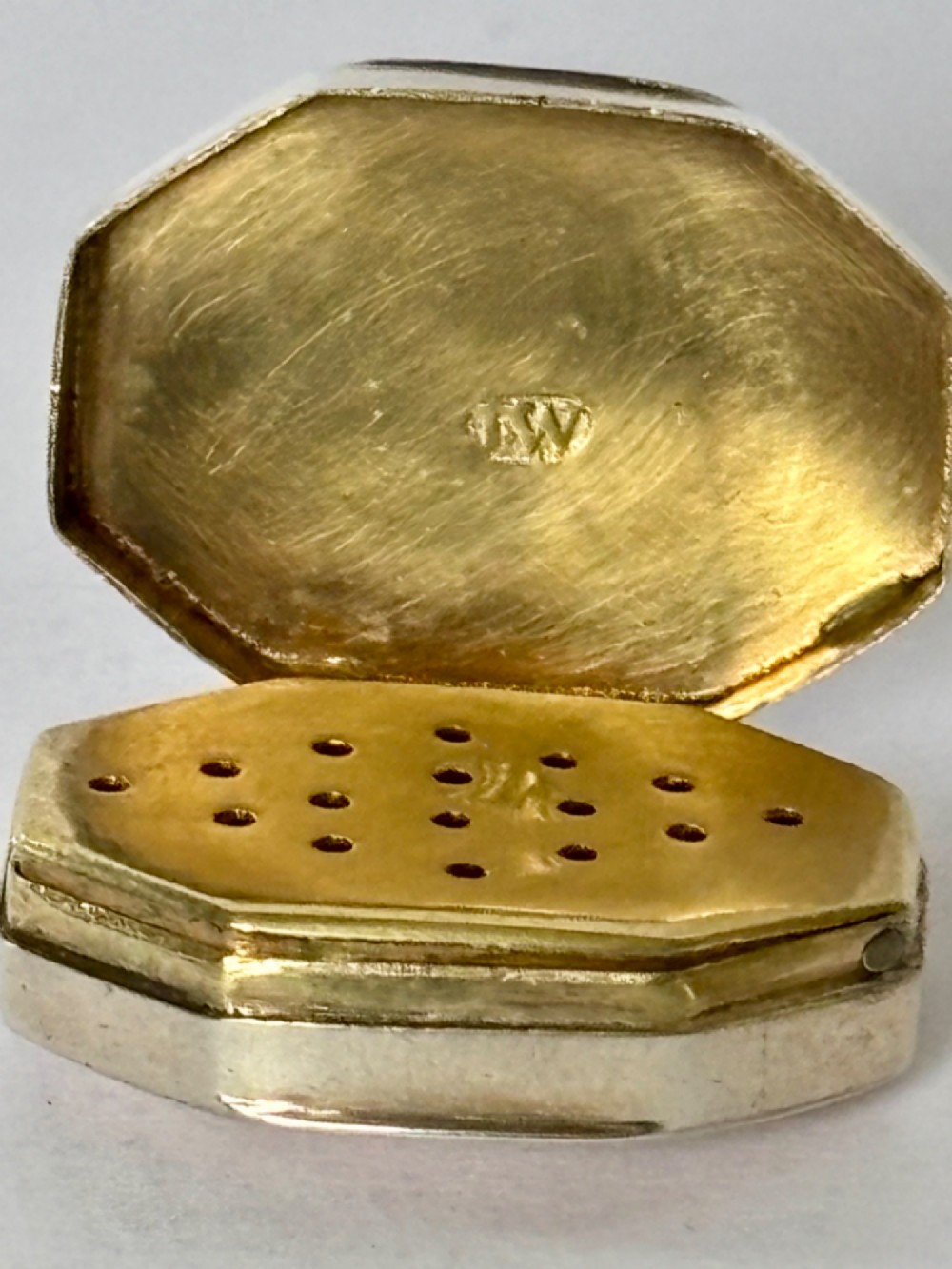 An open George III octagonal sterling silver vinaigrette displaying a gilded interior with a perforated cover and makers stamp. View VII