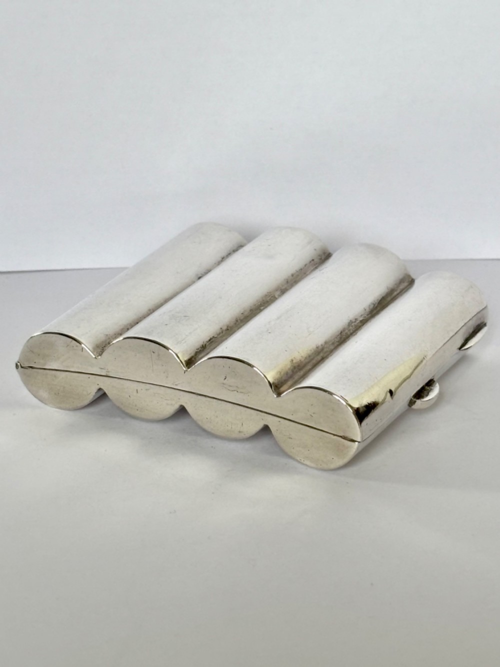 A four-tube sterling silver tobacco cartridge case with a hinged cover and smooth polished finish.