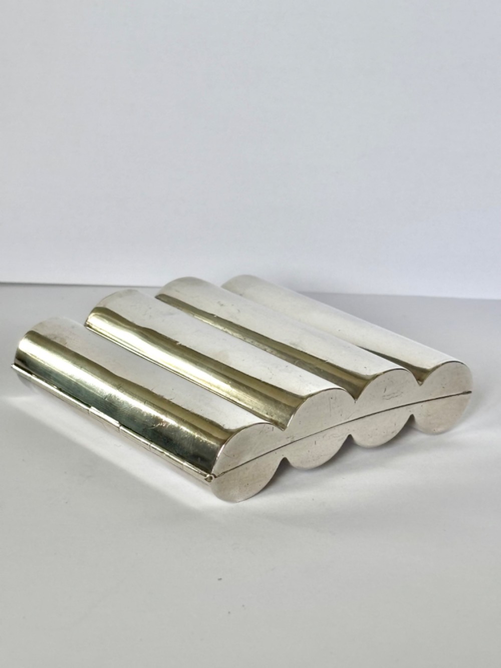 A four-tube sterling silver tobacco cartridge case with a hinged cover and smooth polished finish. View VII