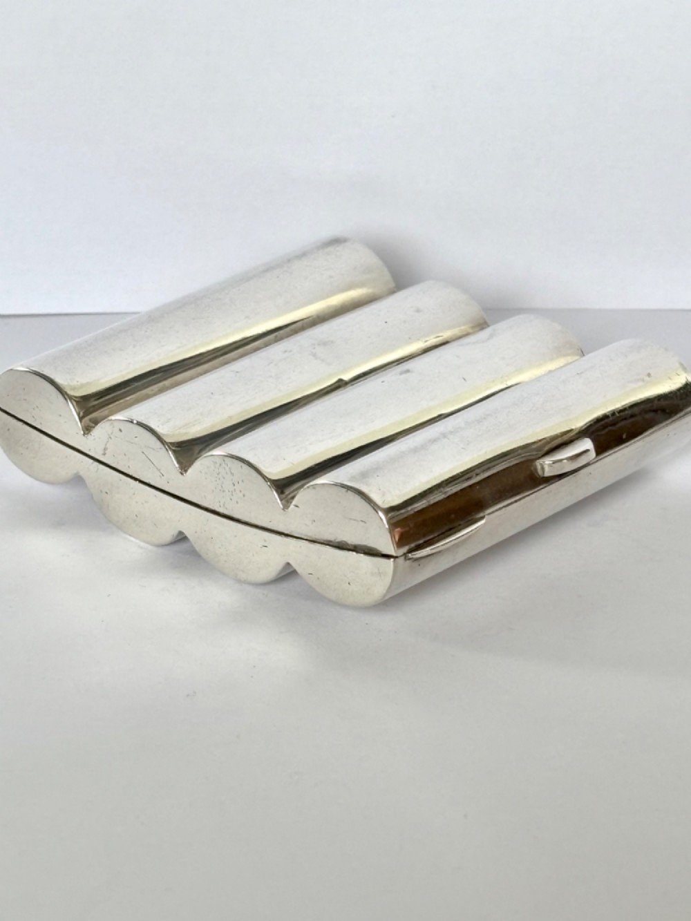 A four-tube sterling silver tobacco cartridge case with a hinged cover and smooth polished finish. View XI