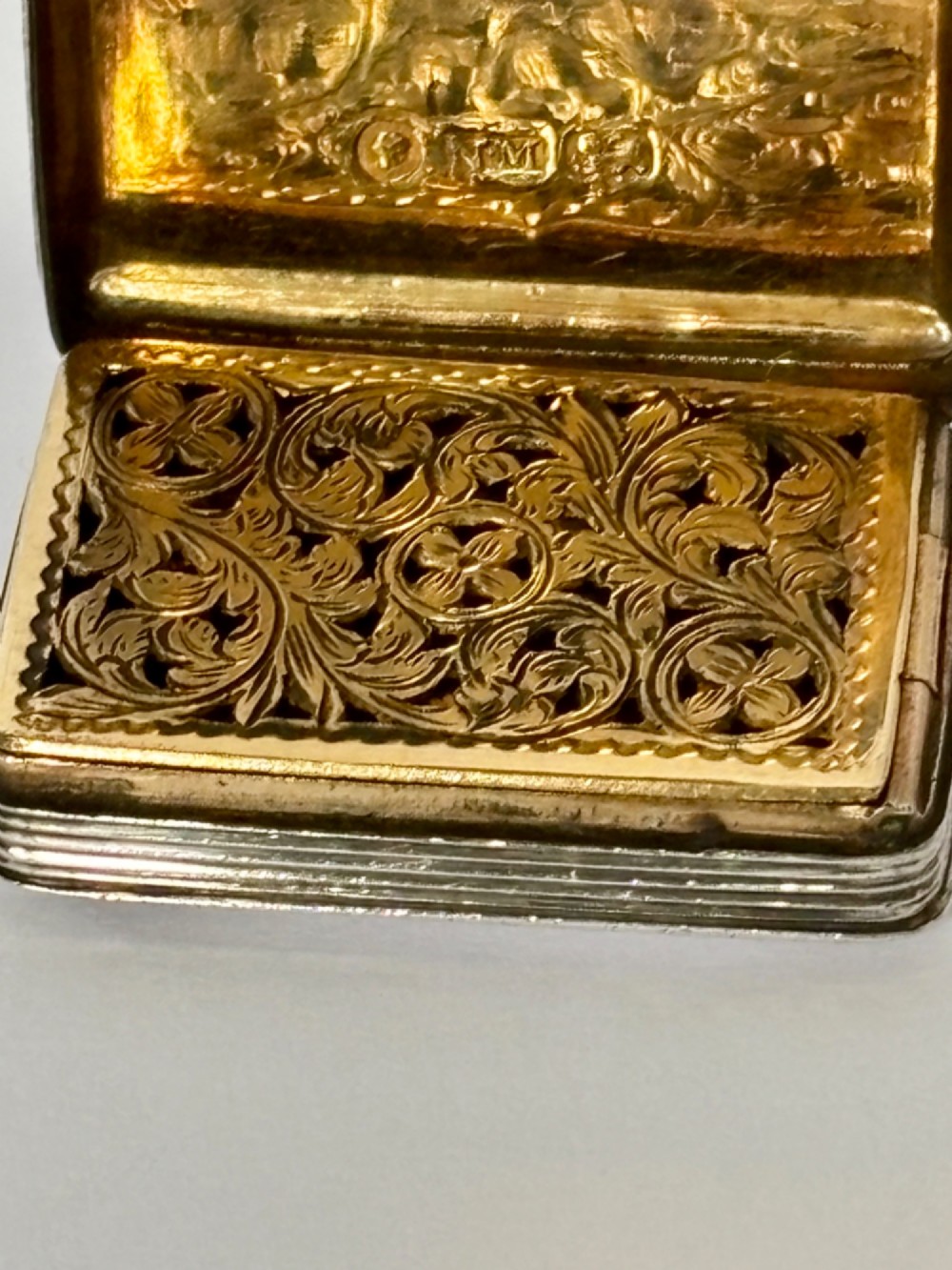 An open Early Victorian silver gilt vinaigrette showing a floral pierced interior grille and hallmarks on the inside lid. View III
