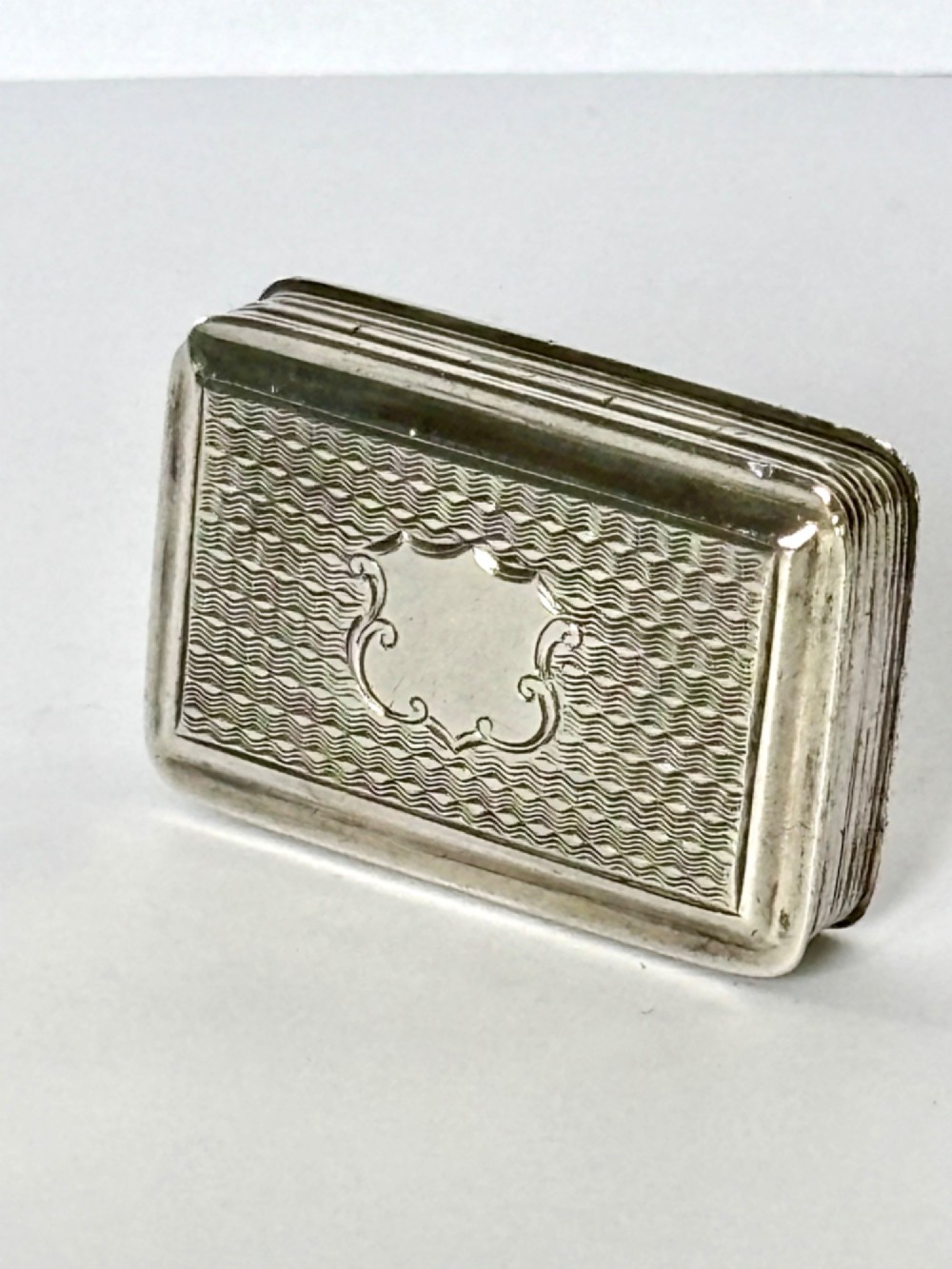 An open Early Victorian silver gilt vinaigrette showing a floral pierced interior grille and hallmarks on the inside lid. View IV