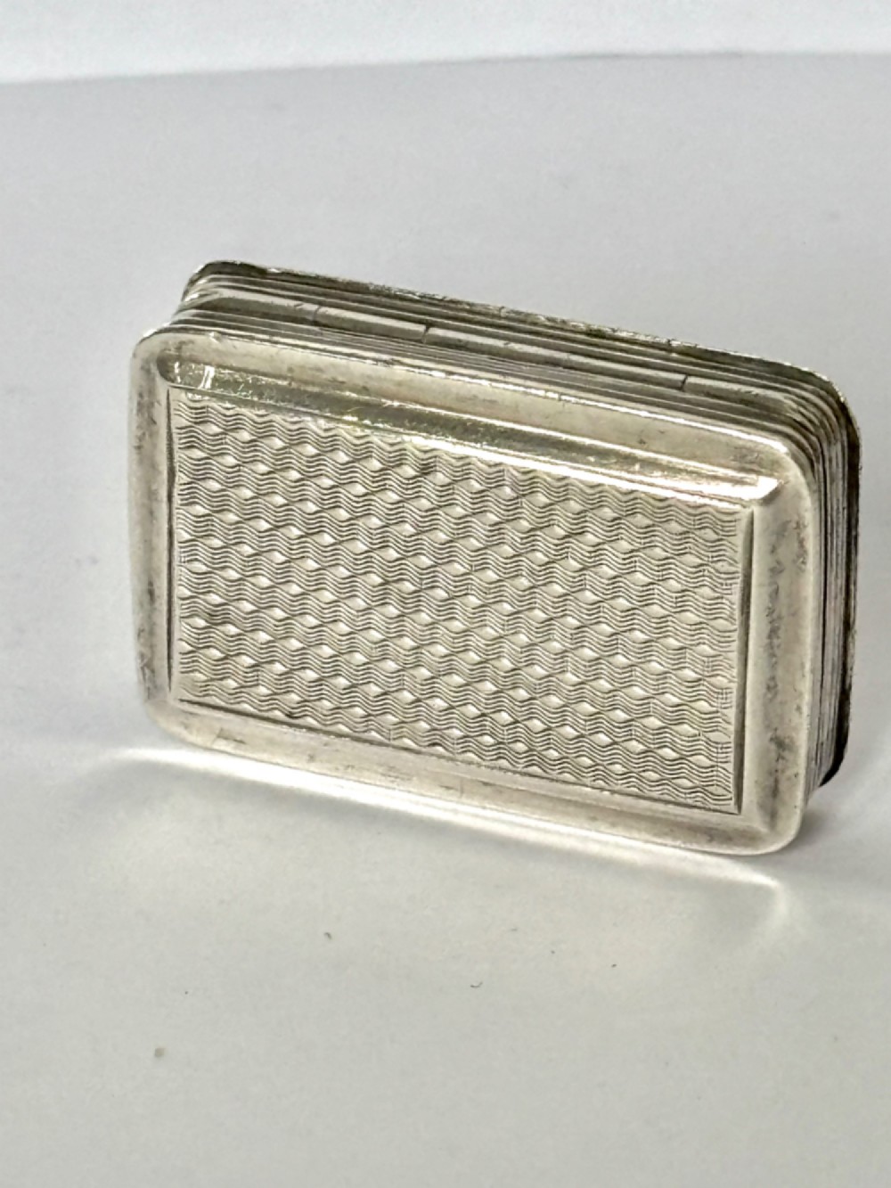 An open Early Victorian silver gilt vinaigrette showing a floral pierced interior grille and hallmarks on the inside lid. View VI