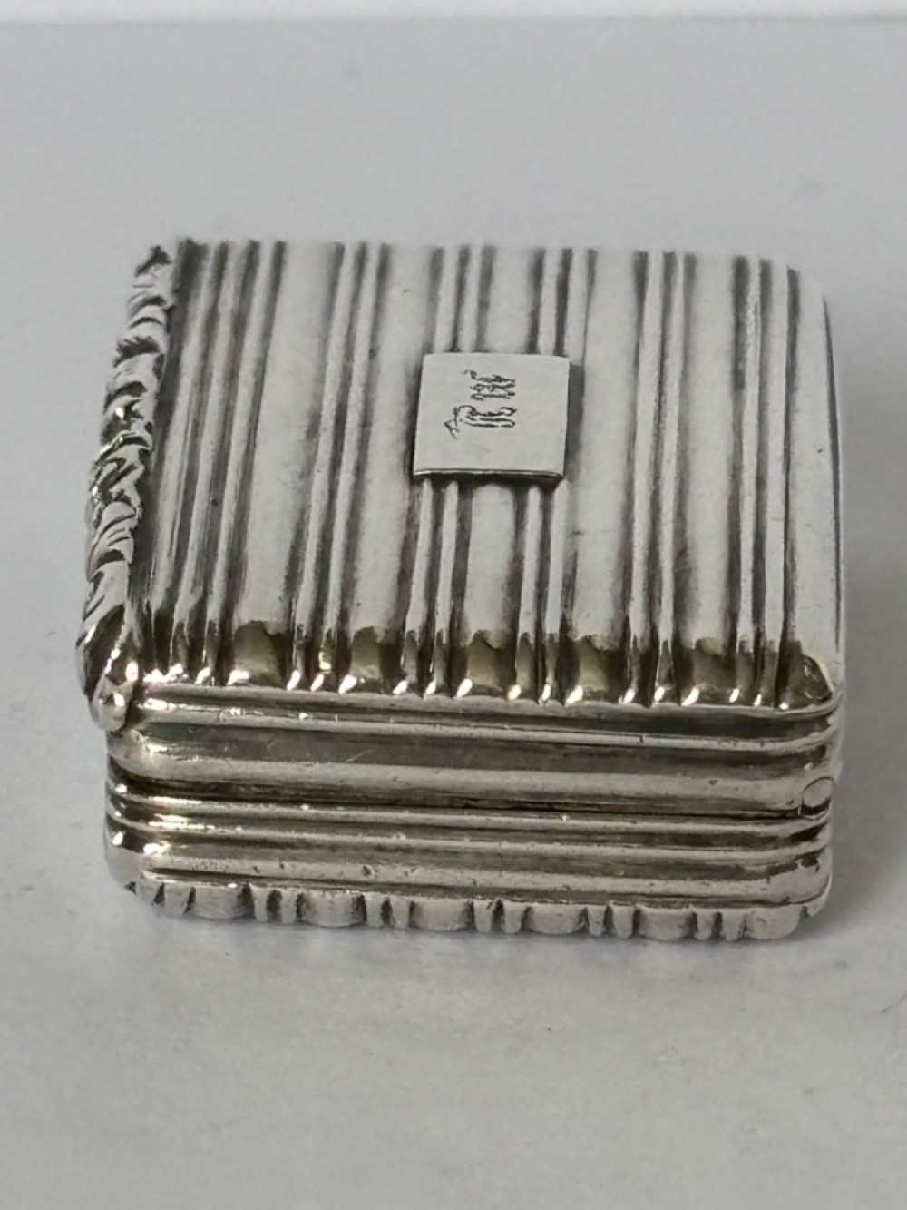 An open George IV rectangular silver-gilt vinaigrette showing internal hallmarks and a hinged pierced grille next to a small dark sponge. View XIII