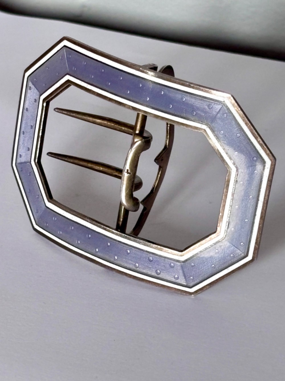 An octagonal antique silver belt buckle featuring lavender guilloche enamel bordered in white enamel with a central metal prong mechanism. View II