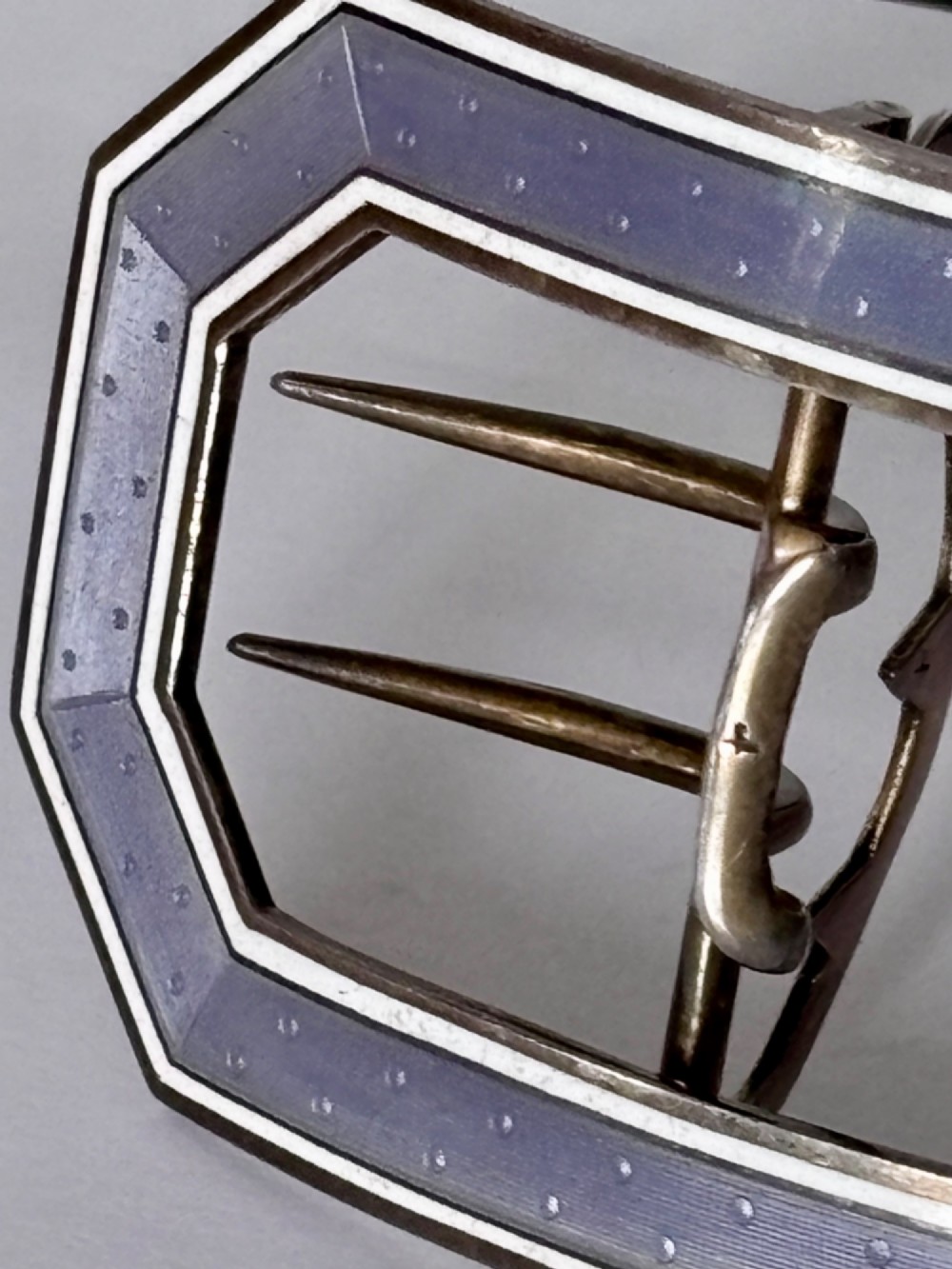 An octagonal antique silver belt buckle featuring lavender guilloche enamel bordered in white enamel with a central metal prong mechanism. View III