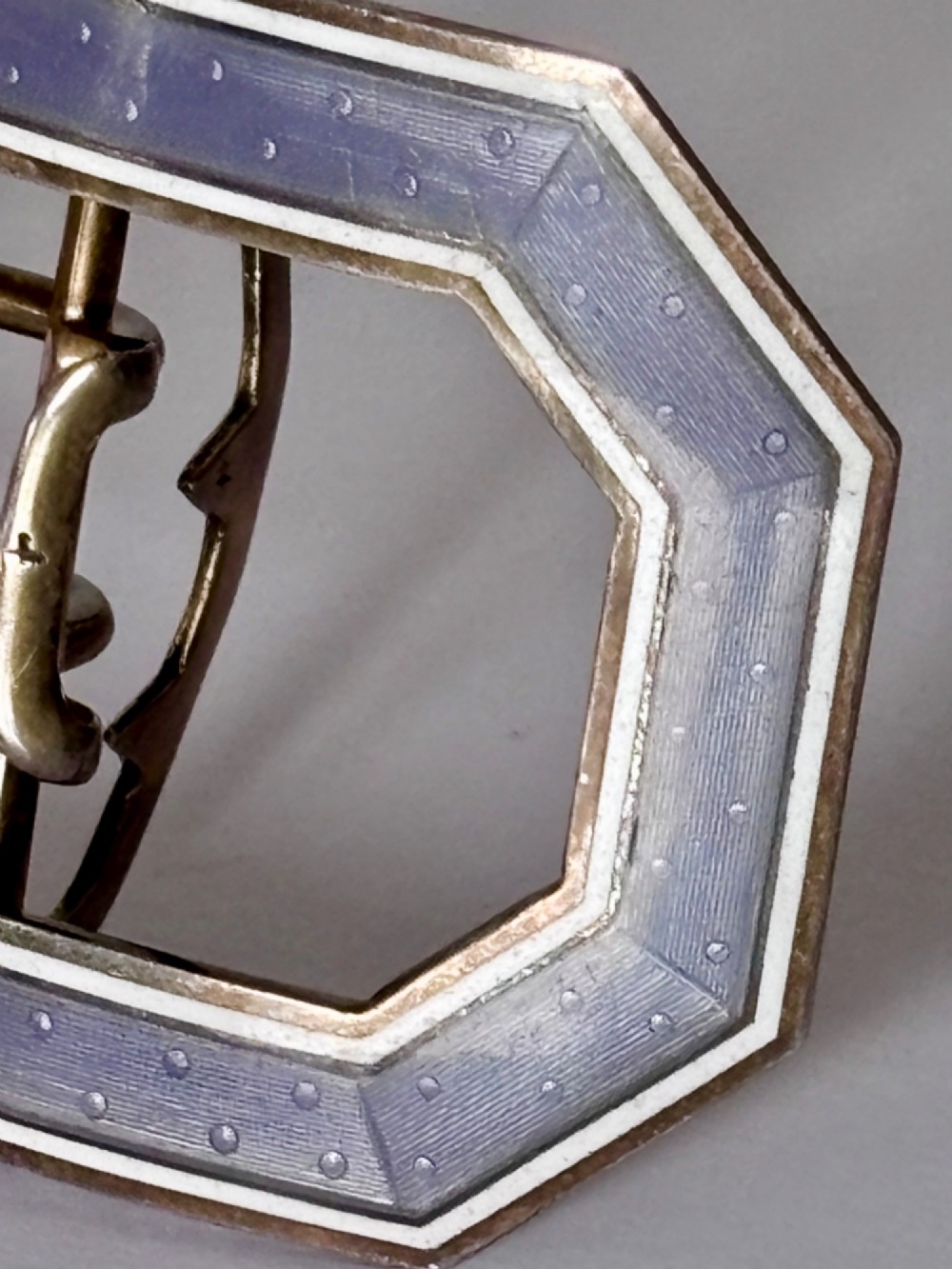An octagonal antique silver belt buckle featuring lavender guilloche enamel bordered in white enamel with a central metal prong mechanism. View IV