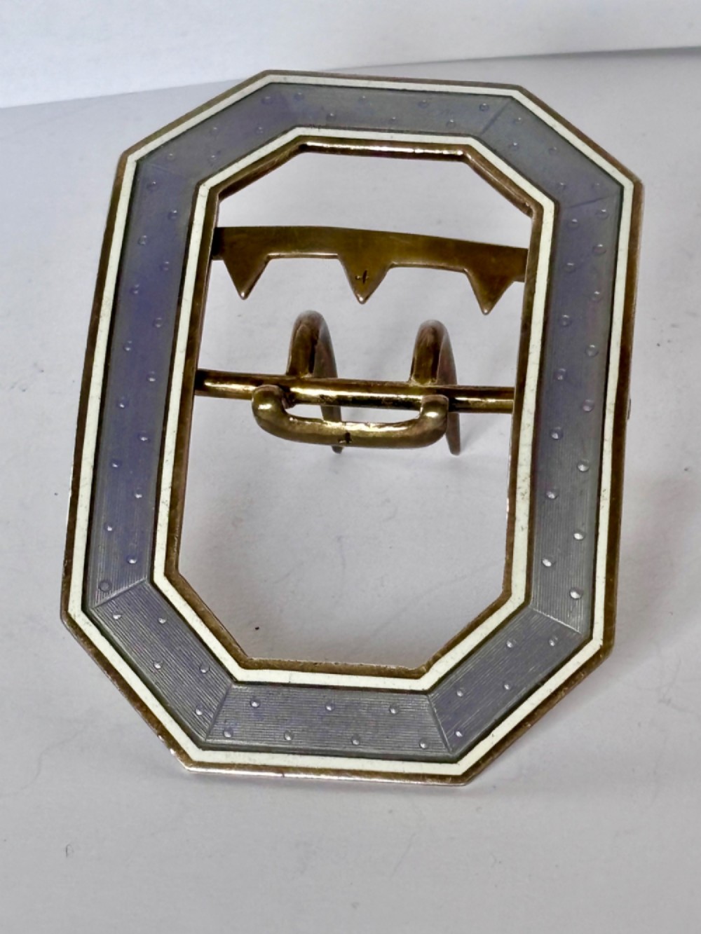 An octagonal antique silver belt buckle featuring lavender guilloche enamel bordered in white enamel with a central metal prong mechanism. View XI