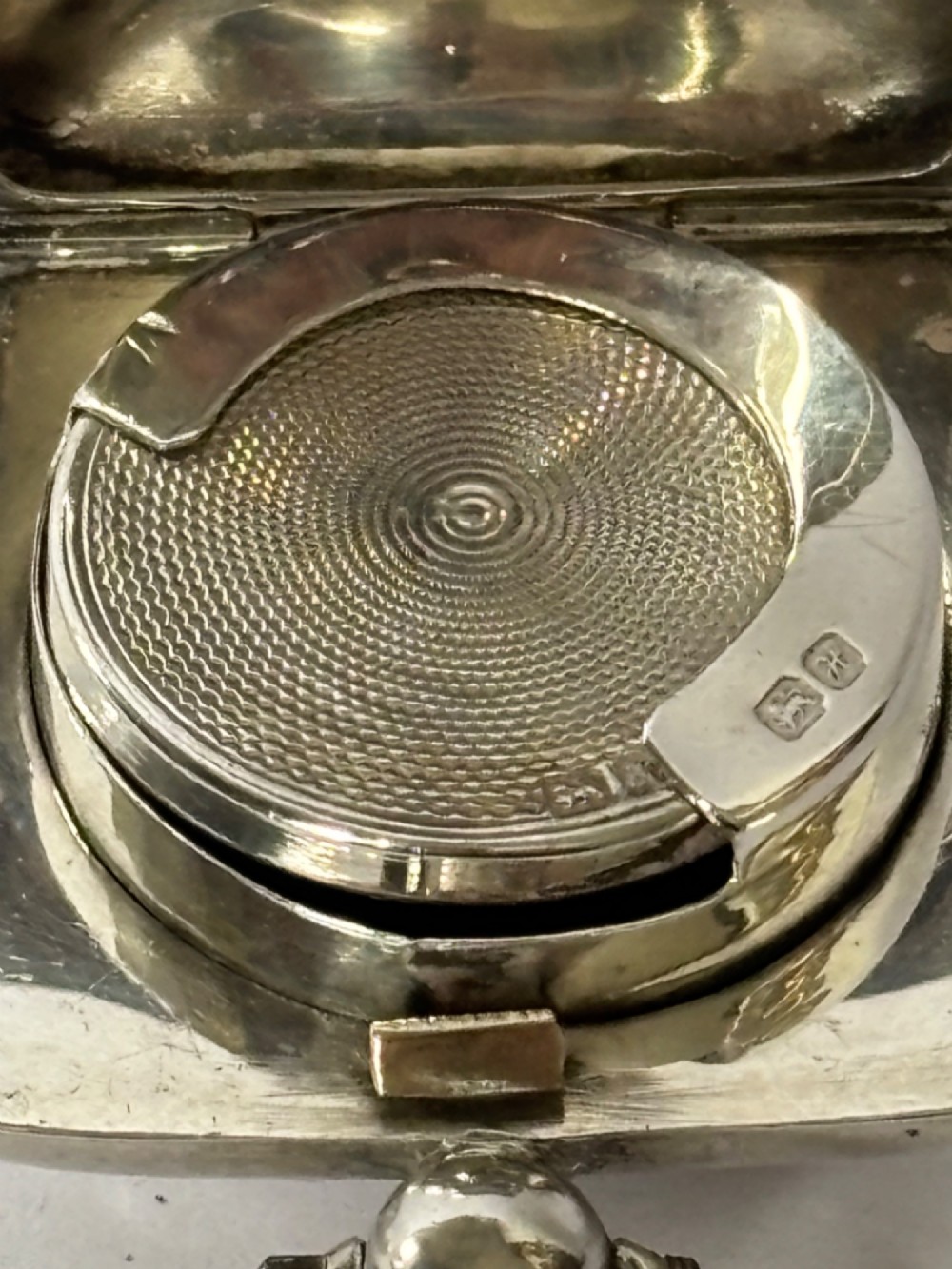 An open Edwardian square sterling silver sovereign case featuring a spring-loaded coin holder and stamped hallmarks on the interior lid. View II