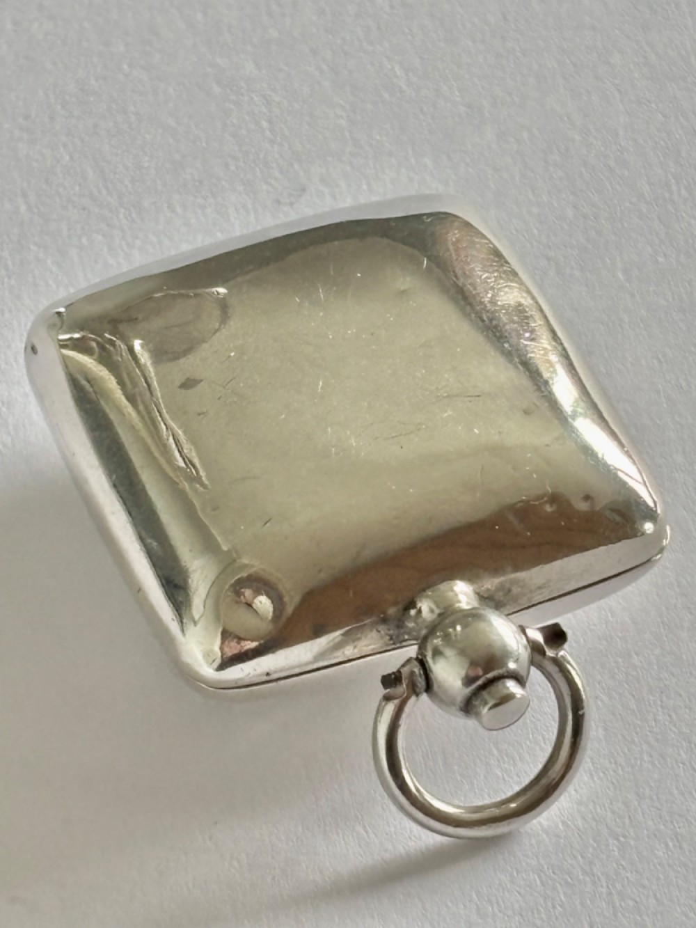 An open Edwardian square sterling silver sovereign case featuring a spring-loaded coin holder and stamped hallmarks on the interior lid. View V