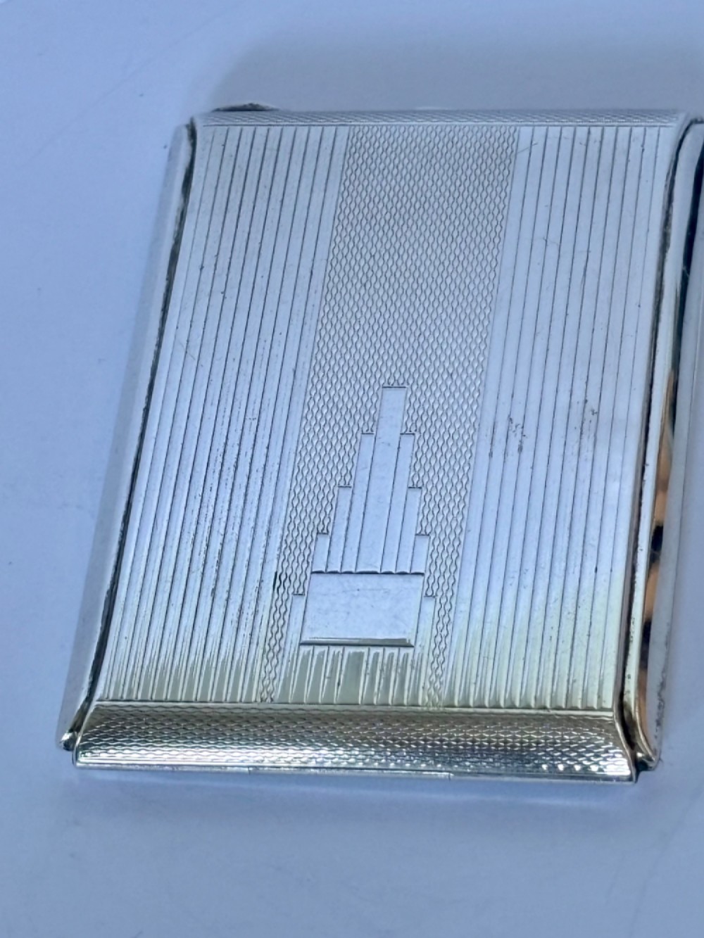 A square sterling silver Art Deco powder compact featuring linear engine-turned patterns and a central geometric stepped motif. View II