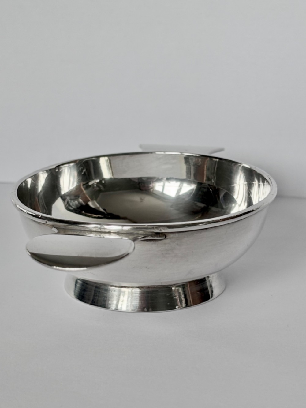 A shallow sterling silver Scottish quaich featuring two flat lug handles and engraved Gaelic lettering in the centre bowl. View V